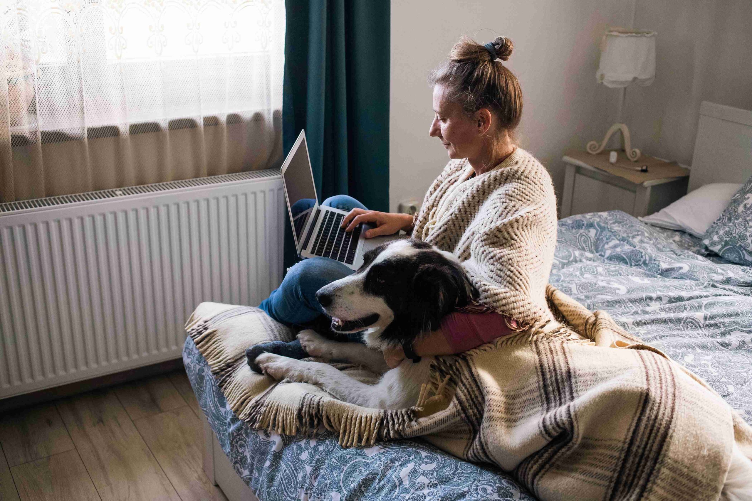 Jeune femme sur son ordinateur avec son chien à côté